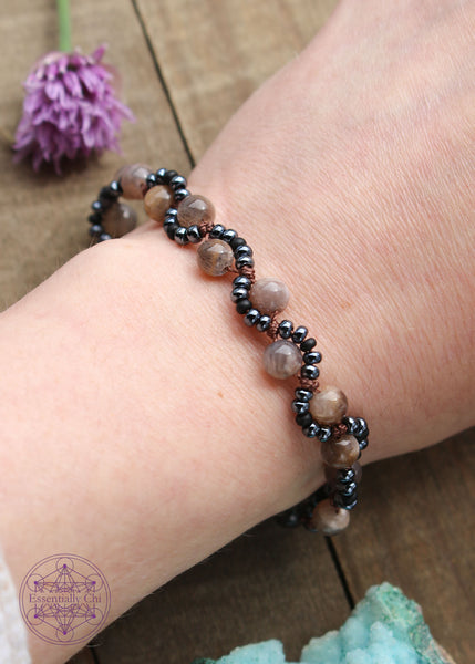 Handknotted beaded boho bracelet with nylon thread in the color chocolate brown. Gemstones are black moonstone. Seed beads are in an S curve on one side or the other of the gemstone in the color hematite color and black, copper hook clasp.