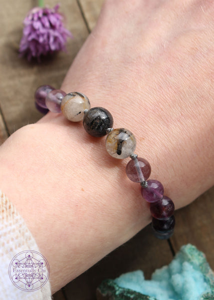 Handknotted beaded boho bracelet with nylon thread in the color grey. Gemstones are Purple Fluorite and Tourmaline Quartz. The TQ is size 10mm in the middle and the purple fluorite on the sides are 8mm beads. Silver plated hook clasp.
