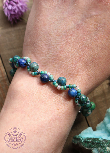 Handknotted beaded boho bracelet with nylon thread in the color blue. Gemstones are dominate azurite with some malachite. Seed beads are in an S curve on one side or the other in the color sea foam green and translucent. Silver plated hook clasp.