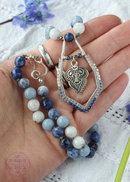 Hand-knotted boho necklace featuring rainbow moonstone, angelite, faceted sodalite, and dumortierite crystals with a silver-plated hook clasp and a beaded mandala pendant, perfect for opening the throat chakra.