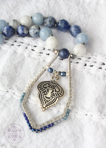 Hand-knotted boho necklace featuring rainbow moonstone, angelite, faceted sodalite, and dumortierite crystals with a silver-plated hook clasp and a beaded mandala pendant, perfect for opening the throat chakra.