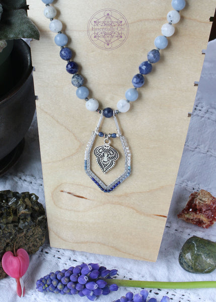 Hand-knotted boho necklace featuring rainbow moonstone, angelite, faceted sodalite, and dumortierite crystals with a silver-plated hook clasp and a beaded mandala pendant, perfect for opening the throat chakra.