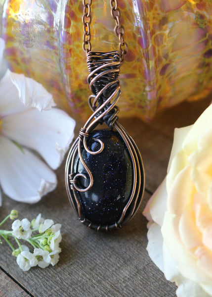 Handcrafted Blue Goldstone Copper Wire Wrapped Pendant - A shimmering gemstone pendant with a mesmerizing night-sky appearance, expertly wrapped in copper wire. This unique piece combines the cosmic allure of Blue Goldstone with the rustic charm of artisan craftsmanship, creating a striking and versatile accessory for crystal enthusiasts.