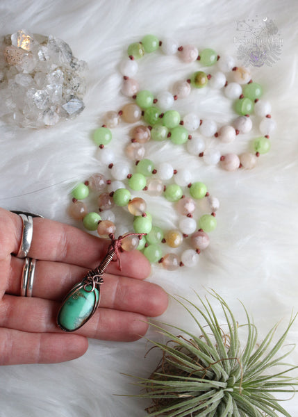 Embrace heart-centered healing with "The Heart Healer" Green Calcite & Chrysoprase Mala Necklace. Hand-knotted with green calcite, rainbow moonstone, and flower agate, it features a copper wire wrapped chrysoprase pendant. Slip it effortlessly over your head for mindful meditation, grounding, and heart chakra activation. Let this mala be your guide to self-love, aligning your heart with its true desires. Elevate your spiritual journey with this unique mala designed for emotional healing and love.