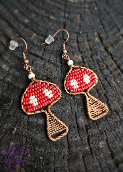 Copper Wire Wrapped mushroom earrings with a red and white beaded Amanita mushroom design. Dangle earrings on brass ear wires.