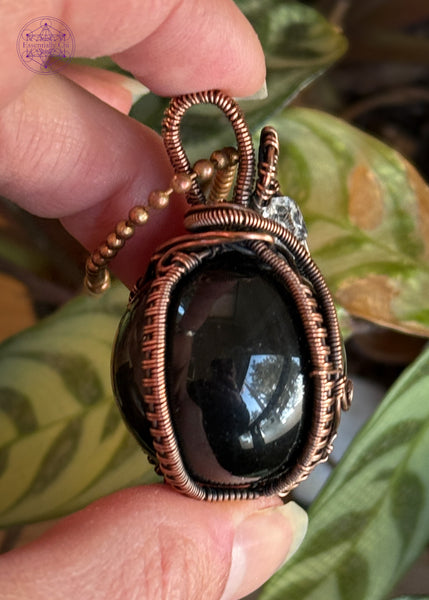 Rainbow Obsidian sphere wrapped in copper wire and an accent diamond quartz in the bail, elegantly wrapped. The Sphere has a green and slightly purple sheen. Showing the side to see how sturdy it is.