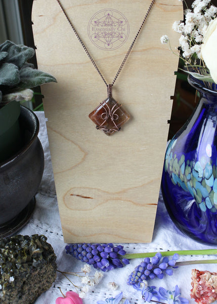 Indulge in the harmonious blend of strength and celestial beauty with our Hematite Garden Quartz Copper Wire Wrapped Necklace. The square-shaped garden quartz, resembling a wrapped package, showcases hematite inclusions, iridescent rainbows, and rutile. This handcrafted masterpiece promotes balance, protection, and a radiant connection to the divine. Perfect for Aries and Aquarius, this unique pendant aligns with the root and crown chakras, making it a symbol of grounding and spiritual elevation.