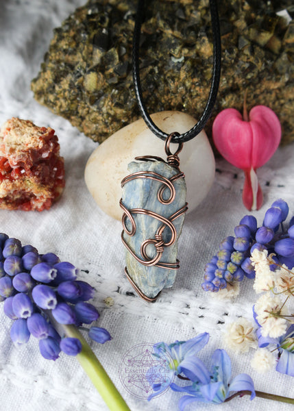 This copper wire wrapped pendant has 4 swirls along the face of the blue kyanite and is connecting the two middle swirls together. This raw crystal has a triangular shape where its flat on the back and pointed in the middle and 1.75" long.  Raw Blue Kyanite Wire Wrapped Necklace for energy protection, featuring a simple, everyday wear design that enhances communication, alignment, tranquility, restful sleep, and dream recall.