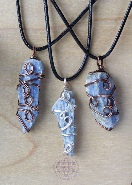 Three wire wrapped raw blue kyanite necklaces on a black waxed cotton cord shown hanging. First one is copper wire, second is silver plated, third is copper wire and a little more chunky. Raw Blue Kyanite Wire Wrapped Necklace for energy protection, featuring a simple, everyday wear design that enhances communication, alignment, tranquility, restful sleep, and dream recall.