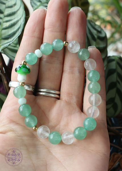 Green & clear fluorite stretch bracelet with round gold colored beads accenting the dark green glass mushroom focal bead.
