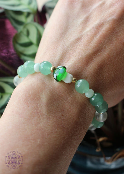 Green fluorite stretch bracelet with round gold colored beads accenting the dark green glass mushroom focal bead.