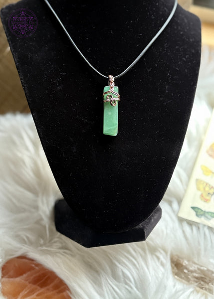 Green Aventurine Copper wire wrapped necklace with a a simple design in the front that looks like hands clasping together and has a braided bail. Hangs on a black cotton wax cord. Shown on a Black velvet bust to show how it hangs worn.