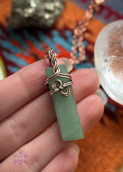 Green Aventurine Copper wire wrapped necklace with a a simple design in the front that looks like hands clasping together and has a braided bail. Hangs on a black cotton wax cord. Shown held in hand for size reference.
