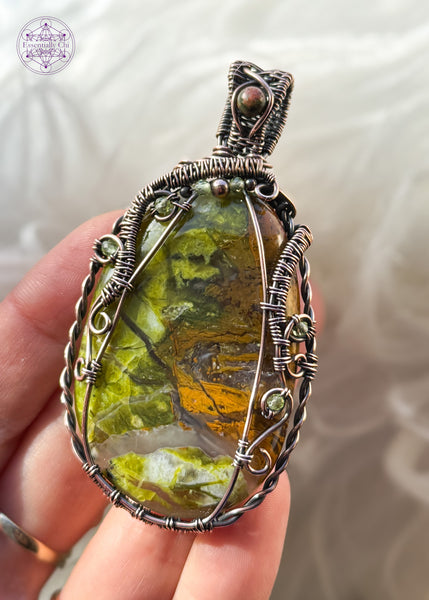 Large green opal flat palmstone wrapped in copper wire with accent stones of 2mm faceted peridot crystals and an unakite crystal in the bail. 2.75" in length and hangs from a copper ball chain. Not very heavy. Held in hand to show size and details up close.