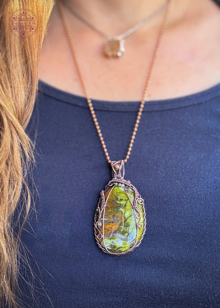 Large green opal flat palmstone wrapped in copper wire with accent stones of 2mm faceted peridot crystals and an unakite crystal in the bail. 2.75" in length and hangs from a copper ball chain. Not very heavy. Shown being worn for size reference.