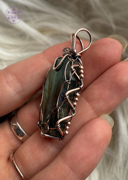 This Labradorite crystal coffin has beautiful hues of yellow, orange, and green, the perfect combo for autumn. Wrapped with a simple viking weave to show off most of the vibrant flash in the labradorite and a simple bail for those who like a minimal jewelry design. Showing the side for details in a zig zag design to secure the viking weave that holds the stone in place.
