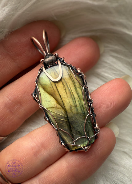 This Labradorite crystal coffin has beautiful hues of yellow, orange, and green, the perfect combo for autumn. Wrapped with a simple viking weave to show off most of the vibrant flash in the labradorite and a simple bail for those who like a minimal jewelry design. Held in hand to show size reference.