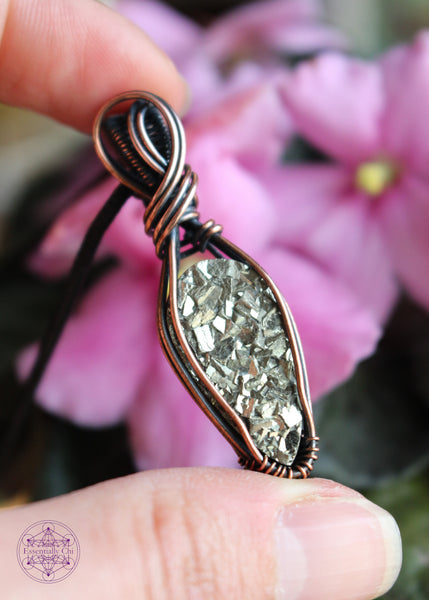 Copper wire wrapped pyrite pendant with a raw face, cubic formation. Simple wrap with double swoop along the bail. Pendant held in hand for size reference.