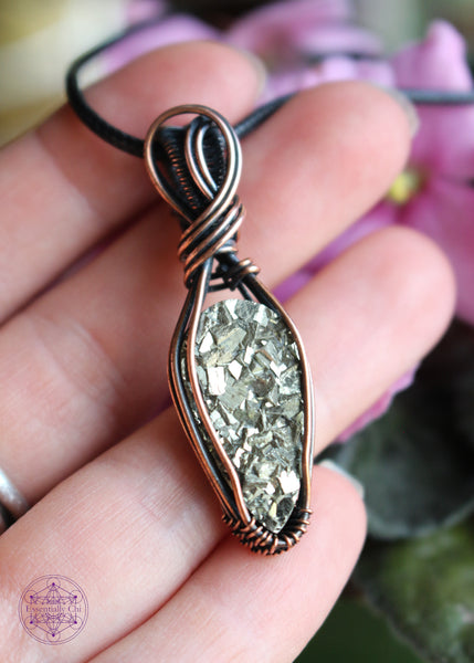 Copper wire wrapped pyrite pendant with a raw face, cubic formation. Simple wrap with double swoop along the bail. Pendant held in hand for size reference.