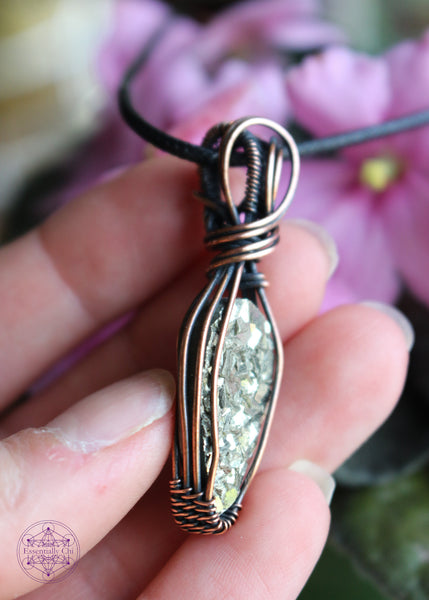 Copper wire wrapped pyrite pendant with a raw face, cubic formation. Simple wrap with double swoop along the bail. Pendant held in hand showing the right side for thickness.