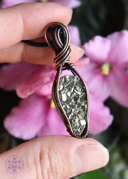 Copper wire wrapped pyrite pendant with a raw face, cubic formation. Simple wrap with double swoop along the bail. Pendant held in hand for size reference.
