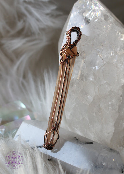 This copper wire wrapped Tangerine Singing Quartz has a twisted copper detail on the sides, and criss cross details on the bottom and at the top of the crystal.
The filagree design includes three faceted smoky quartz woven into the bail. This copper wire wrapped pendant is 2.6" in length and comes on a copper chain. Shown on left side for details.