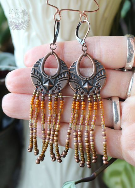 Tree Spirit Copper Fringe Earrings, 3 inches in length with a gradient of brown seed beads and a boho copper charm. Secured with copper lever-back ear wires, these earrings offer handmade elegance with a touch of woodland whimsy