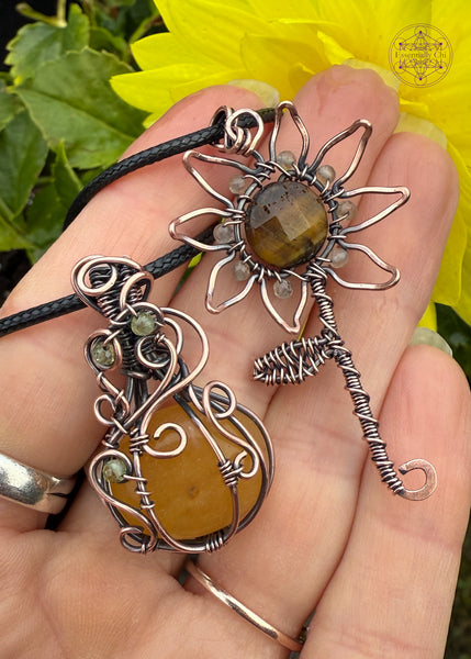 Orange Aventurine mini pumpkin pendant with swirls coming down from the bail and over the front of the pumpkin with three peridot beads in the swirls to act as leaves. Shown next to a sunflower pendant with a tiger eye bead and citrine.