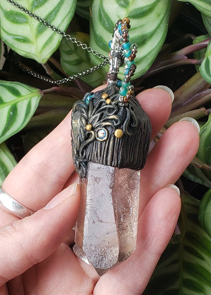 Shop the Garden Fairy Pendant. The Garden Fairy aesthetic is to remind you that when life gets tough, to get out in nature and see what Mother Gaia has given you. This beautiful raw smoky quartz point and rutilated tear drop center stone are paired together to help get you thru life's rough patches with ease. Smoky quartz helps transmute negative energy into positive and rutilated quartz helps you dig into shadow work gently and see the good in yourself. The owl stands for wisdom and protection.
