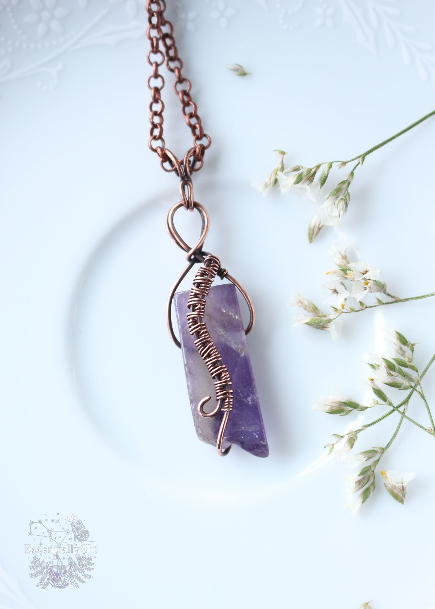 Embrace the spirit of adventure with our Avandra Chevron Amethyst Copper Wire Wrapped Pendant. Named after the goddess of freedom, this piece enhances intuition, promotes emotional balance, and alleviates stress, with an S-curve weave down the front of the crystal symbolizing the journey's importance. Ideal for Aquarius energy.