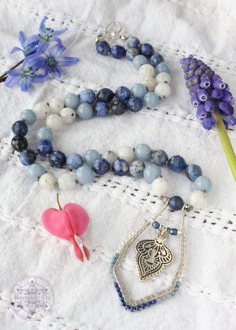 Hand-knotted boho necklace featuring rainbow moonstone, angelite, faceted sodalite, and dumortierite crystals with a silver-plated hook clasp and a beaded mandala pendant, perfect for opening the throat chakra.