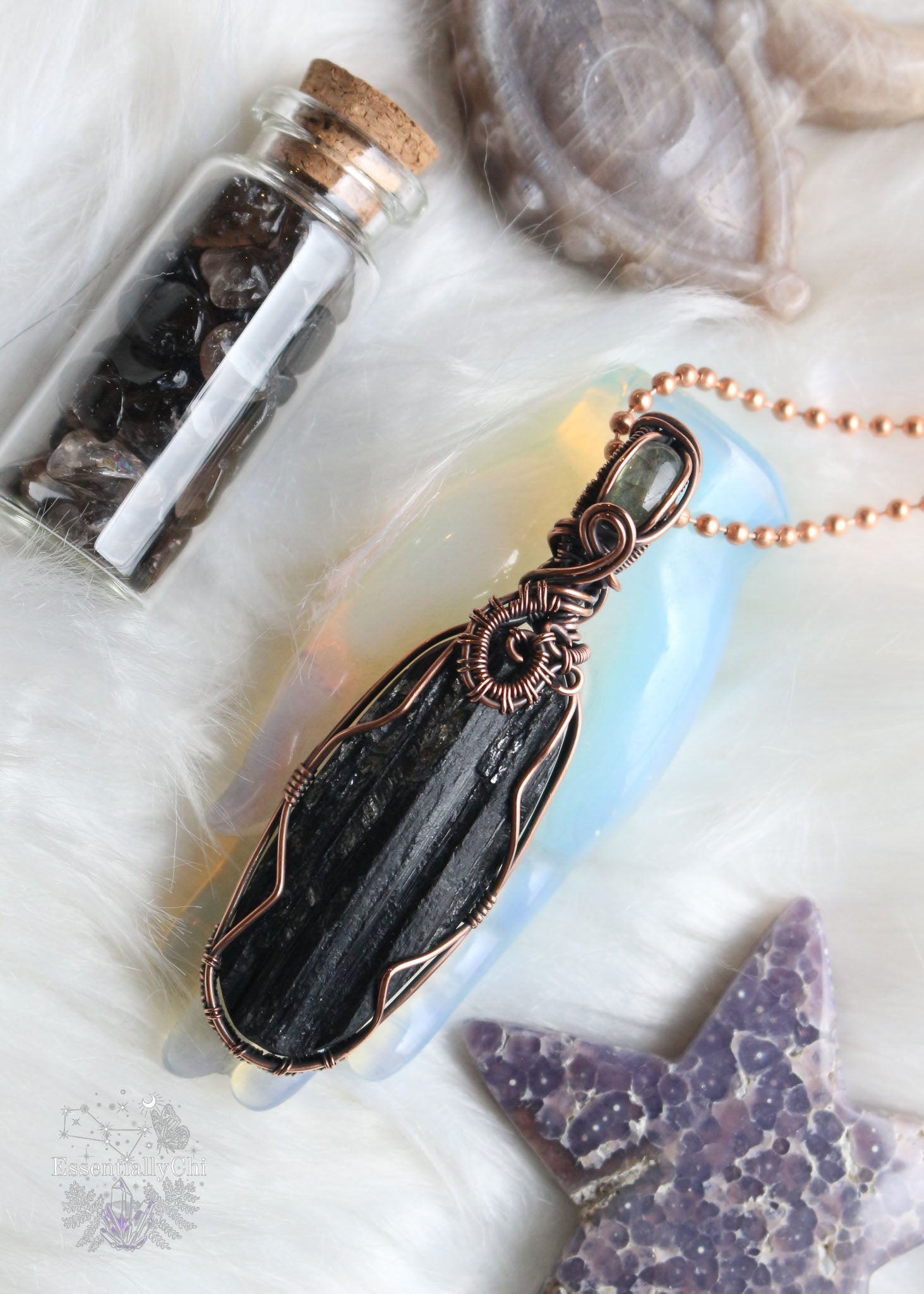 A captivating Black Tourmaline and Labradorite Wire Wrapped Necklace – a synergy of protection and mysticism. The raw-faced Black Tourmaline, guardian of grounding energy, meets the enchanting Labradorite with its green-yellow flash, enhancing intuition and spiritual connection. Elevate your style and energy with this handcrafted gem, designed for those who seek both protection and magic. Pendant is 2.9" in length.