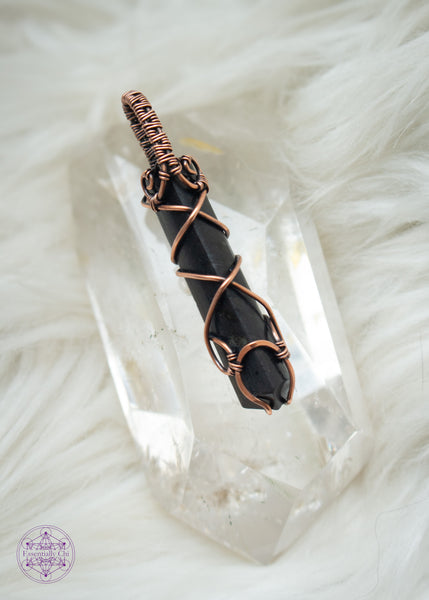 Black Tourmaline point wrapped in copper wire with a criss cross design up the front and a simple woven bail. This protection crystal is great for a minimalist and can be unisex. Showing the front of the pendant that is sitting on clear quartz to highlight the details.