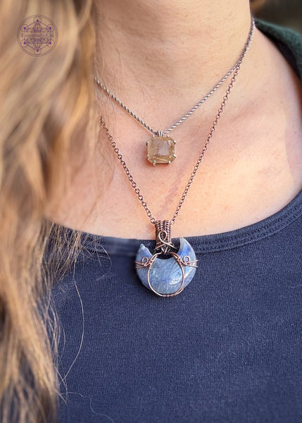 Copper wire wrapped blue aventurine half moon with a simple copper wire wrapped design. Shown worn with a blue shirt.
