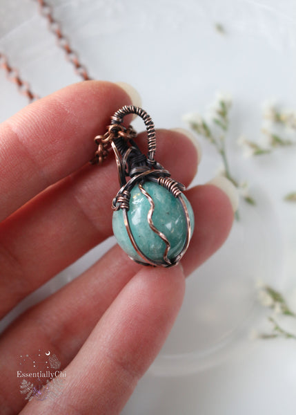 Discover the wisdom of our Sophia Filigree Amazonite Copper Wire Wrapped Mini Sphere Pendant. This reversible design features a high-quality 17mm Brazilian Amazonite sphere, promoting harmony, creativity, and emotional balance—an ideal accessory for empaths seeking to align their energy.