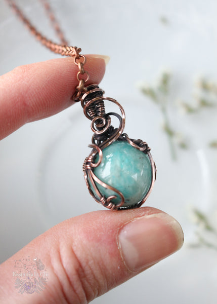 Discover the wisdom of our Sophia Filigree Amazonite Copper Wire Wrapped Mini Sphere Pendant. This reversible design features a high-quality 17mm Brazilian Amazonite sphere, promoting harmony, creativity, and emotional balance—an ideal accessory for empaths seeking to align their energy.