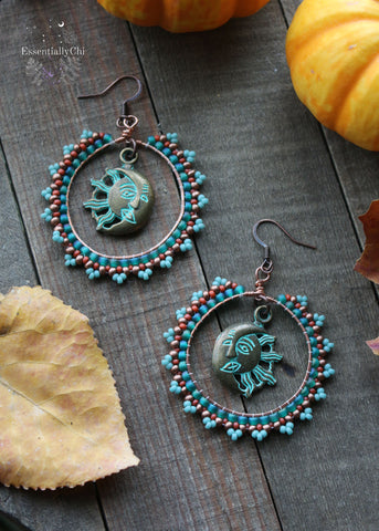 Celestial Beaded Boho Hoop Earrings featuring a turquoise, terra cotta, brass, and aqua green seed bead pattern. Brass sun and moon charm at the center of the 1.9-inch diameter hoops, hanging 2.5 inches from copper ear hooks. A cosmic expression of bohemian style