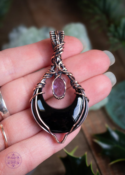 Lilith is a black onyx and faceted amethyst copper wire wrapped pendant. She's a black crescent moon facing upwards (curve side down) and above the moon is the faceted amethyst that captures the light. Shown in hand for size reference.