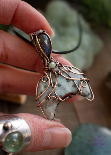 Copper wire wrapped whale tail with the main stone as Kiwi Jasper half moon in a filigree design with accent stones of sea foam green tourmaline and labradorite. The bail has a gorgeous deep blue flash labradorite. Held in had to show off the flashes in the Labradorite. 