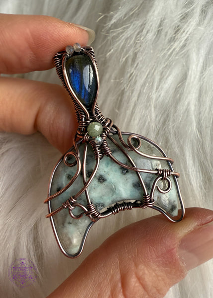 Copper wire wrapped whale tail with the main stone as Kiwi Jasper half moon in a filigree design with accent stones of sea foam green tourmaline and labradorite. The bail has a gorgeous deep blue flash labradorite. Held in had to show off the flashes in the Labradorite. 