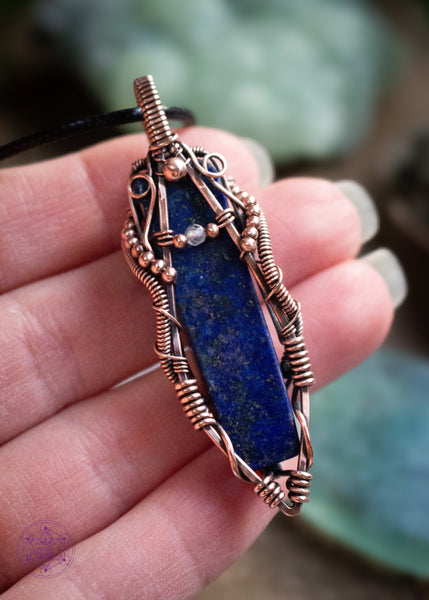 Lapis Lazuli copper wire wrapped necklace with a moonstone accent bead. The design looks like the curves of a woman holding a small moonstone bead. The Lapiz Lazuli is so dark with the flecks of pyrite within that mimmic the night sky. Hence why I named this pendant Asteria after the goddess of the night sky. Held in hand to show size reference.