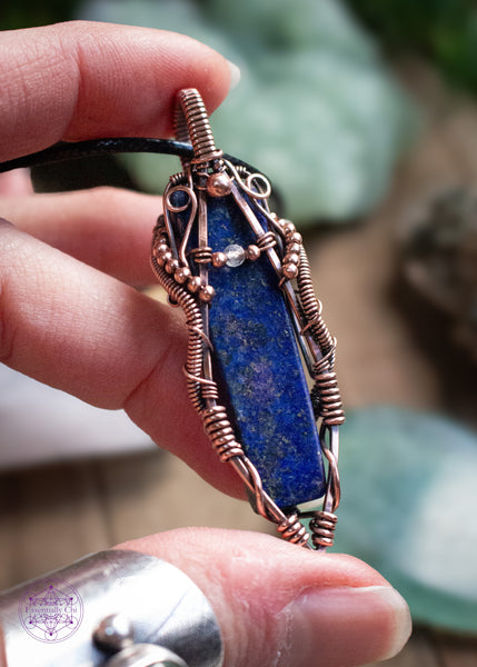 Lapis Lazuli copper wire wrapped necklace with a moonstone accent bead. The design looks like the curves of a woman holding a small moonstone bead. The Lapiz Lazuli is so dark with the flecks of pyrite within that mimmic the stars in the night sky. Hence why I named this pendant Asteria after the goddess of the night sky. Shown in hand with the light reflecting off the pyrite flecks.