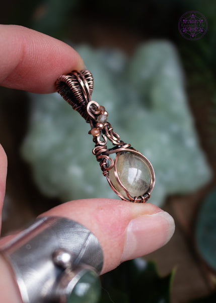 This copper wire wrapped pendant has a small round golden rutile crystal and accent crystal beads of sunstone and citrine that catch the light and really make this pendant sparkle like stardust! Shown in hand and displaying the sides so you can see how thin this design is. Lightweight and dainty.