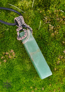 green aventurine pendant wrapped with copper wire and a black cotton waxed cord. The crystal is a rectangle and the copper wrapping is close to the bail showing more of the stone.