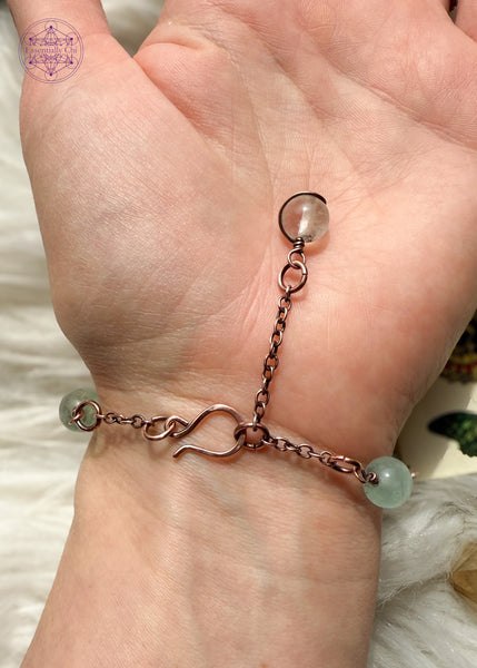Copper wire wrapped bracelet features 8mm green Fluorite beads individually wrapped with figure 8 Infinity links in-between for an elegant bracelet. Showing the backside of bracelet on wrist to see hook clasp and beaded extension chain and green fluorite charm that you can hold onto to secure the clasp.