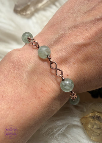 Copper wire wrapped bracelet features 8mm green Fluorite beads individually wrapped with figure 8 Infinity links in-between for an elegant bracelet. Shown on wrist to see how it lays. 