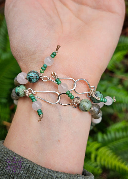 Hand-knotted beaded boho bracelets in a pastel pink and green theme. Showing the back of the bracelets with a silver plated hook closure and seed bead tassel.