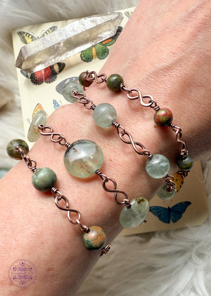 picture of four different crystal bracelets with the infinity links shown worn on wrists with crystals displayed in the background. 