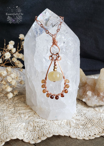 Hessonite Garnet and Yellow Jade Pumpkin Copper Wire Wrapped Necklace - A graceful celebration of autumn and warm hues, promoting vitality, joy, and wisdom. The hessonite garnet beads have an ombre color gradient along the bottom of the pendant and the yellow jade pumpkin dangles in the middle of the teardrop hoop setting.  This is a very elegant design for those who love autumn jewelry and warm tones. 