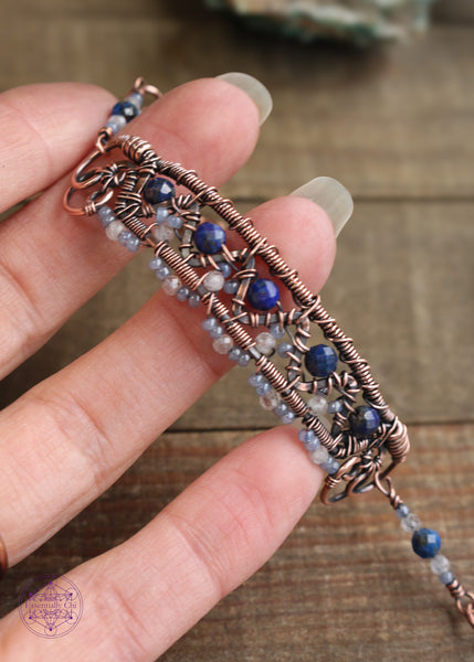 Copper wire wrapped bracelet features faceted lapis lazuli and moonstone woven between a zig zag design and added smoky blue seed beads for a filagree look. This bracelet is very detailed and sure to catch peoples eye! Shown holding in hand to bring out the details. 